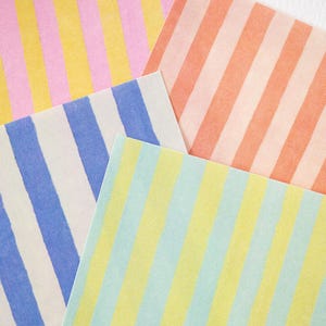 May include: Four sheets of paper with vertical stripes in various colors. The colors include pink and yellow, peach, blue and white, and yellow and light blue. The sheets are arranged in a fan-like pattern.
