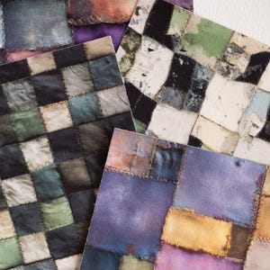 May include: Close-up of several fabric squares with a patchwork design. The squares feature a variety of colors, including purple, black, green, and tan. Each square is stitched together with visible thread, creating a textured effect. The overall theme is a vintage or handcrafted textile.
