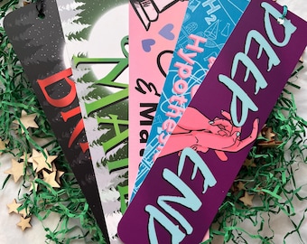 May include: Five colorful bookmarks with different designs and text. The bookmarks are made of cardstock and have tassels. The designs include a forest scene, a chess piece, a science theme, and a hand with the text "Deep End".