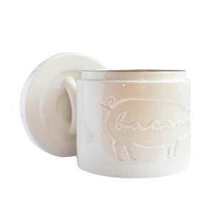 May include: White ceramic canister with a lid, featuring a pig silhouette with the word "bacon" inscribed on it.