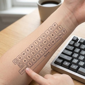Peut inclure: Un tatouage temporaire sur un avant-bras représentant un clavier QWERTY noir. Le motif comprend des touches de lettres individuelles, des signes de ponctuation, une barre d'espace marquée "Space", des touches "Yes", "No", "I LOVE YOU", un smiley et une frimousse triste.