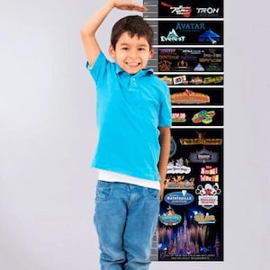Puede incluir: Un gráfico de crecimiento negro de altura de atracciones de Disney World con orejas de Mickey Mouse. El gráfico muestra nombres de atracciones como Avatar y Everest. Un niño con camisa azul y vaqueros está al lado.