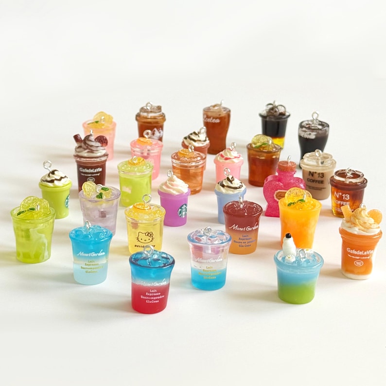 Puede incluir: Una colecci&oacute;n de dijes en miniatura con forma de bebidas de varios colores y estilos, incluyendo vasos de pl&aacute;stico transparente con resina l&iacute;quida, algunos con crema batida, rodajas de fruta o menta, cada uno con una peque&ntilde;a argolla met&aacute;lica.