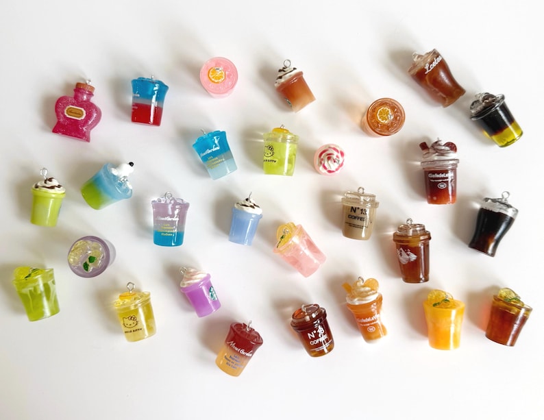 Puede incluir: Una colecci&oacute;n de dijes en miniatura con forma de bebidas de diversos colores y estilos, incluyendo tazas de caf&eacute;, vasos de refresco y bebidas frutales. Cada dije cuenta con una peque&ntilde;a argolla met&aacute;lica en la parte superior para colgar.