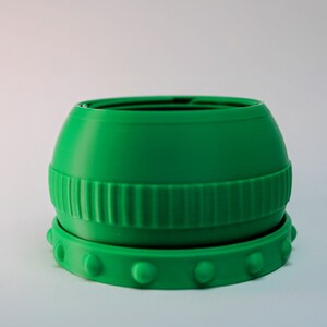 May include: A green plastic container with a textured lid and a ring of raised dots around the bottom.
