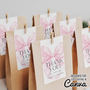 Może przedstawiać: Kilka brązowych papierowych torebek na prezenty z białymi etykietami z różową kokardą i napisem "THANK YOU!" w kolorze czarnym. Etykiety są przymocowane małymi drewnianymi spinaczami. Widoczny jest tekst "Designed for easy editing in Canva".