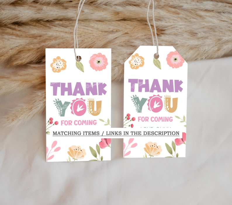 Pode incluir: Duas etiquetas de presente brancas com desenhos florais e as palavras "THANK YOU FOR COMING" em roxo, verde e laranja. As etiquetas t&ecirc;m um cord&atilde;o para pendurar e s&atilde;o decoradas com flores e folhas.