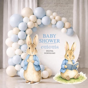 Op de afbeelding: Baby shower uitsparingen met Peter Konijn illustraties. De scène bevat een ballonnenboog in wit en lichtblauw, en een witte cirkelvormige achtergrond met tekst. Er zijn twee konijn uitsparingen aanwezig, waarvan één een boek vasthoudt.