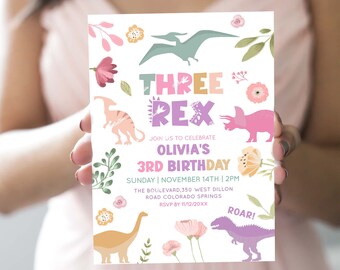 Può includere: Un invito di compleanno a tema dinosauri rosa e verde per il 3° compleanno di una bambina. L'invito presenta il testo "THREE REX" e "Olivia's 3rd Birthday". Include anche la data, l'ora e il luogo della festa. L'invito è decorato con fiori e dinosauri.