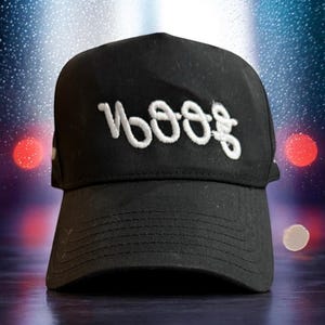 Può includere: Un cappello da camionista nero con un logo ricamato bianco che dice "WOOOF".