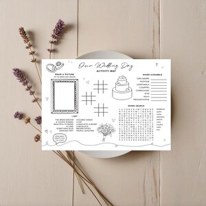 May include: A white wedding activity mat with the text "Our Wedding Day" and various games, including a word search, word scramble, and an "I Spy" section. The mat also features a space to draw a picture of the bride and groom.