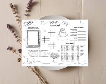 May include: A white wedding activity mat with the text "Our Wedding Day" and various games, including a word search, word scramble, and an "I Spy" section. The mat also features a space to draw a picture of the bride and groom.
