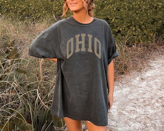 Könnte beinhalten: Ein dunkelgraues Oversize-T-Shirt mit dem Wort "OHIO" in brauner, gewölbter Schrift.