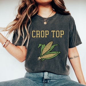 May include: A dark gray crop top with a yellow graphic that says "CROP TOP" and a green and yellow corn illustration.