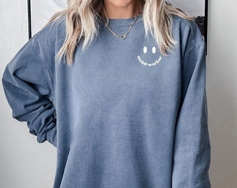 Puede incluir: Una sudadera azul con una cara sonriente blanca y el texto "social worker" debajo.