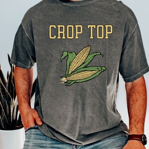 May include: A gray t-shirt with the text "Crop Top" and a graphic of corn on the front.