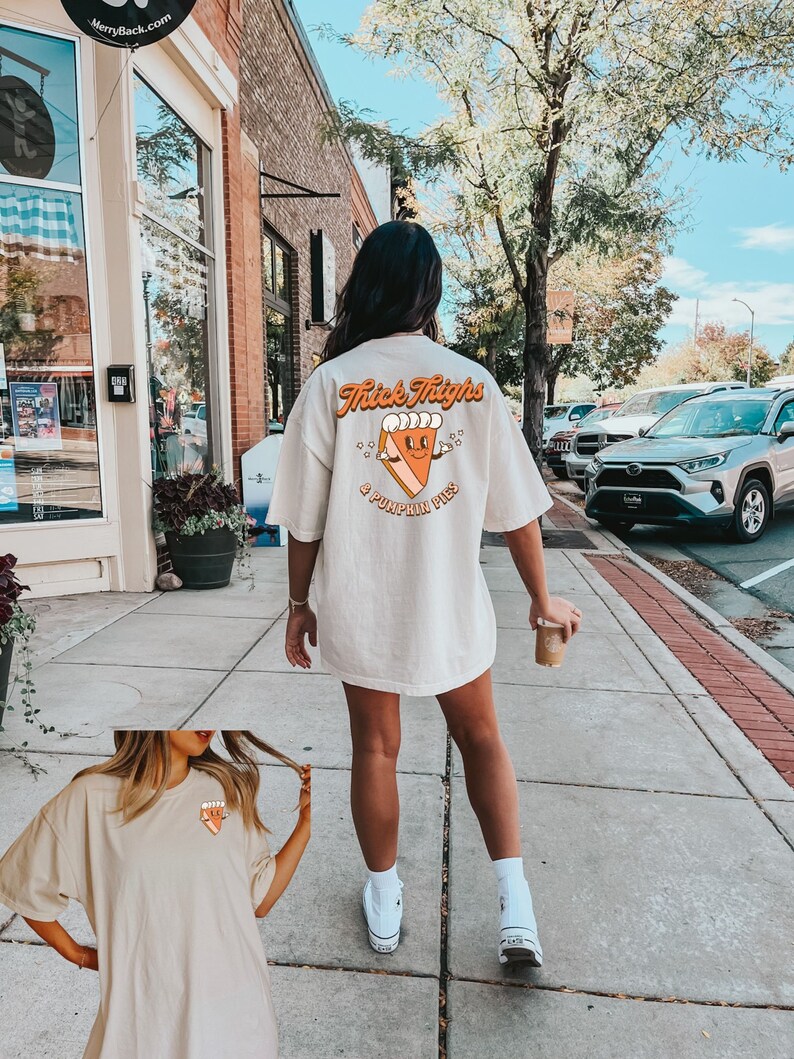May include: A beige oversized t-shirt with a graphic of a pumpkin pie with the text "Thick Thighs & Pumpkin Pies".