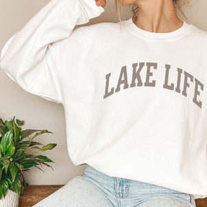 以下が含まれることがあります： グレーの「LAKE LIFE」の文字がアーチ状に書かれた白いスウェットシャツ