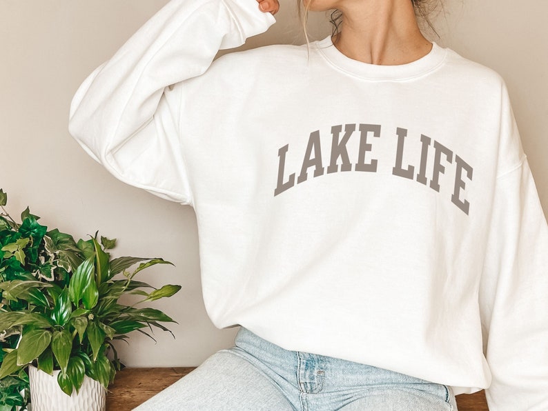 以下が含まれることがあります： グレーの「LAKE LIFE」の文字がアーチ状に書かれた白いスウェットシャツ