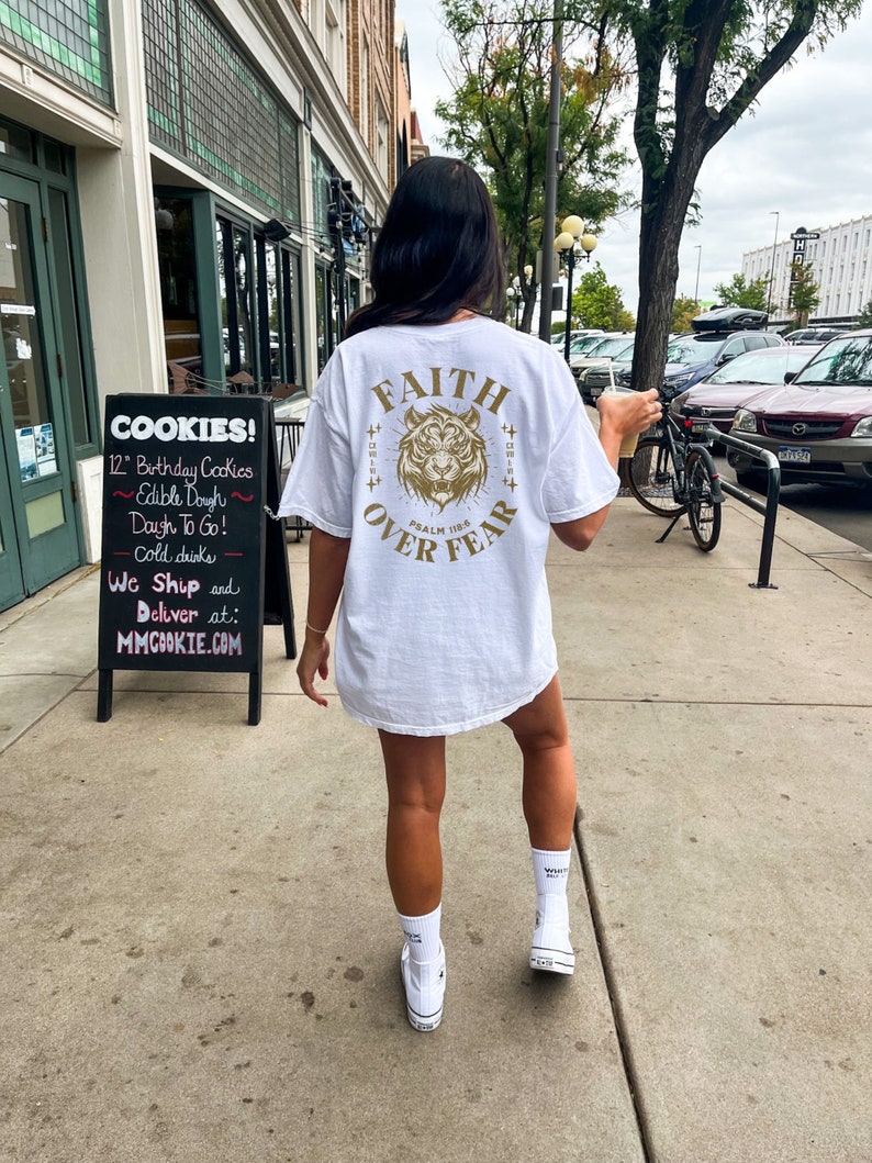 May include: White t-shirt with a gold tiger graphic and the text "FAITH OVER FEAR" and "PSALM 118" printed on the back.