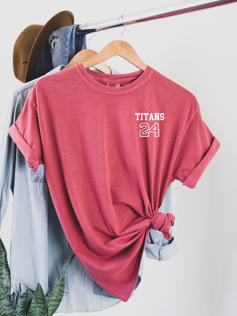 May include: A red t-shirt with the words "TITANS 24" printed on the front in white.