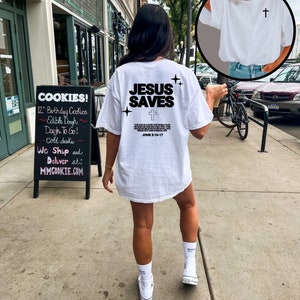 May include: White t-shirt with the text "JESUS SAVES" and a cross graphic. The text "JOHN 3:16-17" is also included on the shirt.