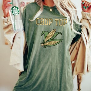 May include: A green oversized t-shirt with the text "CROP TOP" in yellow letters and a graphic of two ears of corn.