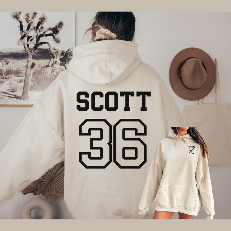 May include: A cream-colored hoodie with a black print of the name "SCOTT" and the number "36" on the back.