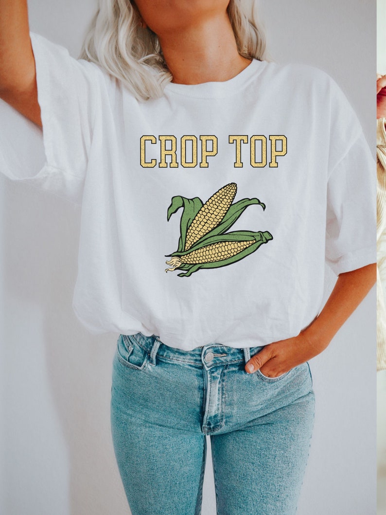 May include: White crop top with the text "CROP TOP" in yellow letters and a graphic of two ears of corn.