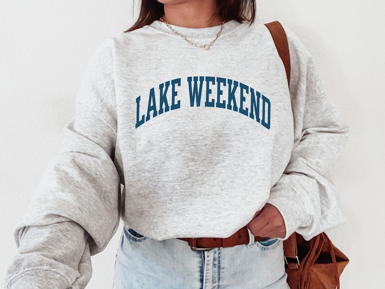 May include: A gray sweatshirt with the text "LAKE WEEKEND" in blue lettering.