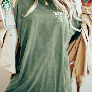 May include: A green oversized t-shirt with the text "TIGERS 14" printed on the front.