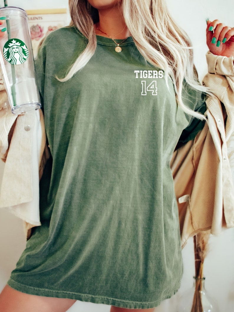 May include: A green oversized t-shirt with the text "TIGERS 14" printed on the front.