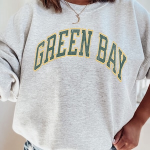 May include: Gray sweatshirt with the text "GREEN BAY" in green and yellow letters.