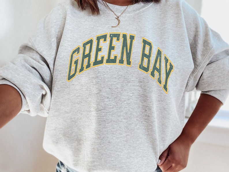 May include: Gray sweatshirt with the text "GREEN BAY" in green and yellow letters.