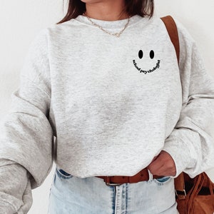 May include: A gray sweatshirt with a black smiley face and the text "actual psychology" printed on the front.