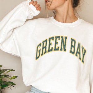 May include: White sweatshirt with a green and yellow "Green Bay" graphic.