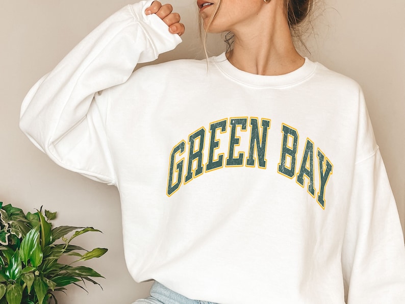 May include: White sweatshirt with a green and yellow "Green Bay" graphic.