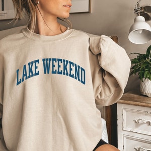 May include: A beige sweatshirt with the text "LAKE WEEKEND" in blue lettering.