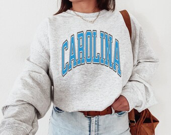 May include: Gray sweatshirt with a blue "CAROLINA" graphic on the front. The sweatshirt has a relaxed fit and is perfect for casual wear.