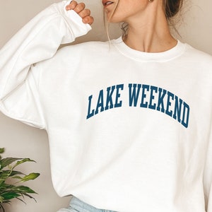 May include: White sweatshirt with a navy blue arch design that reads "LAKE WEEKEND".
