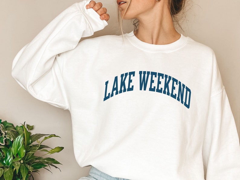 May include: White sweatshirt with a navy blue arch design that reads "LAKE WEEKEND".