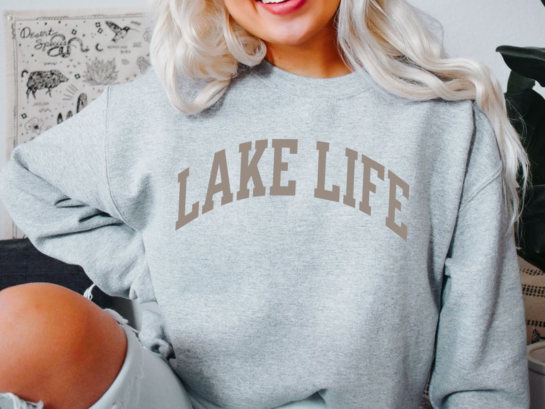 以下が含まれることがあります： グレーのトレーナーに、茶色の文字で「LAKE LIFE」と書かれています。
