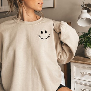 May include: A beige sweatshirt with a black smiley face and the text "behavior matters" printed on the front.