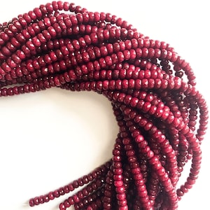May include: A strand of deep red faceted glass beads. The beads are small and round, and they are strung together on a clear thread.