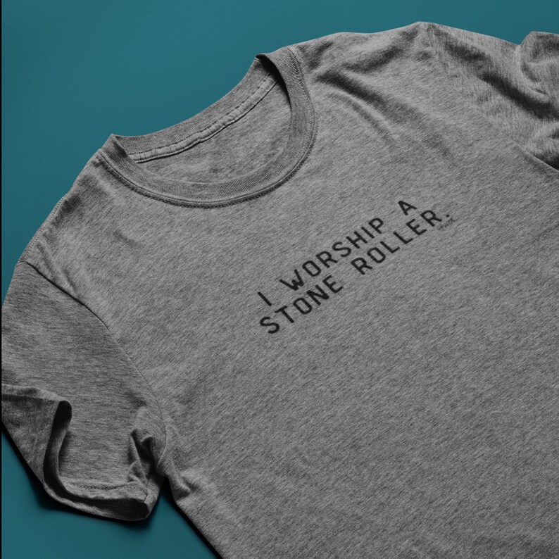 May include: A heather grey t-shirt with the text "I worship a stone roller." printed on the front.