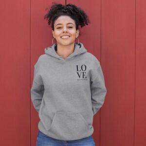 May include: A gray hooded sweatshirt with the words "LOVE YOUR NEIGHBOR" printed on the front.