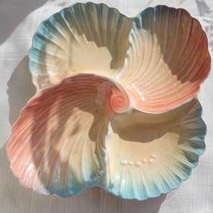 May include: A multi-sectioned serving dish in the shape of a stylized flower or shell. The dish features a colour gradient from light blue to peach and cream. The centre has a spiral design. The dish is likely ceramic or porcelain.