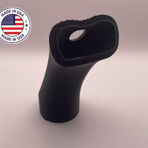 以下が含まれることがあります： 上部に穴のある黒い湾曲したオブジェクト。オブジェクトは、テクスチャ加工されたリムと滑らかで丸みを帯びたベースを備えています。「MADE IN USA」の文字とアメリカ国旗が入った丸いステッカーが左上にあります。