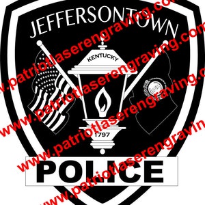 May include: Black and white police badge with the words "Jeffersontown Police" and "Kentucky" in white text. The badge features a stylized lamp with a flame and the year "1797" below it. The badge is surrounded by a black shield shape with a white border.