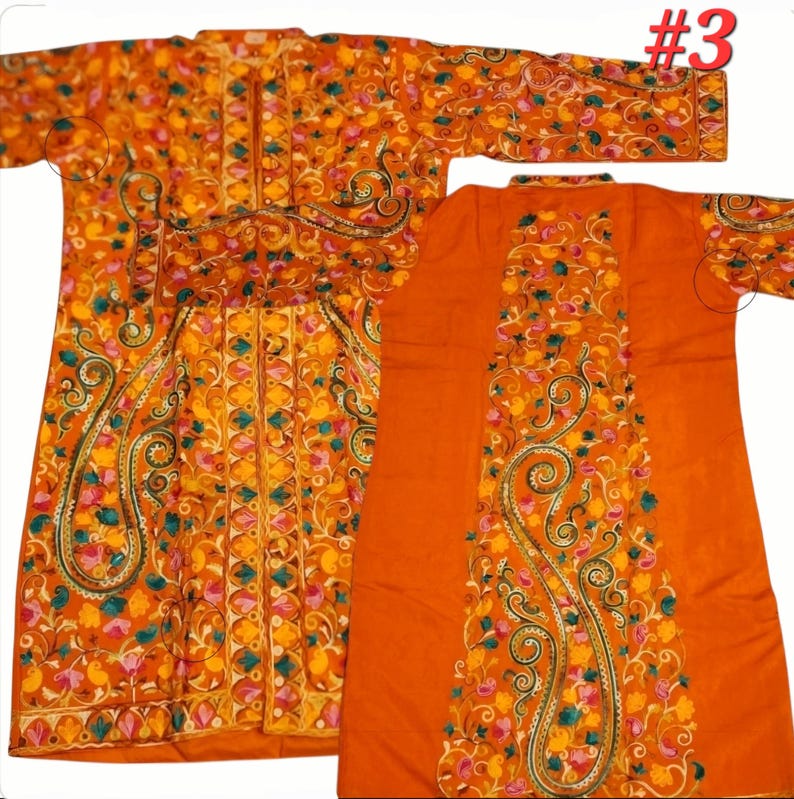 Op de afbeelding: Een oranje, lange mouwen kledingstuk met gedetailleerde bloemenborduurwerk in geel, roze en teal. Het kledingstuk heeft een paisley design en een bijpassende rug. Het nummer "#3" is zichtbaar in de rechterbovenhoek.
